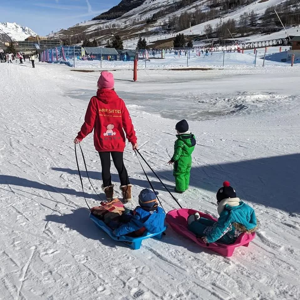 Anne tire deux luges sur le front de neige des Deux Alpes