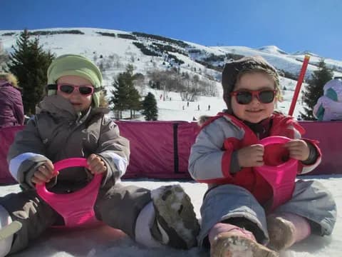 Deux enfants avec leurs luges au pied des pistes