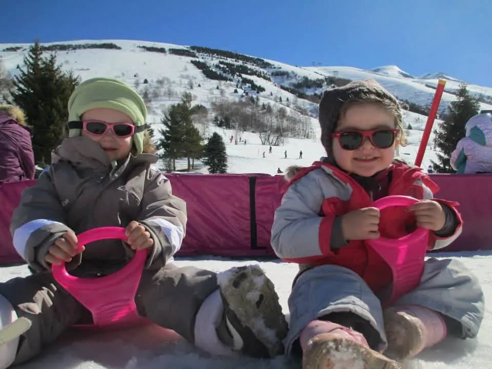 Deux enfants avec leurs luges au pied des pistes