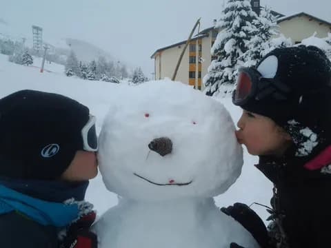 Deux enfants font un bisou au bonhomme de neige